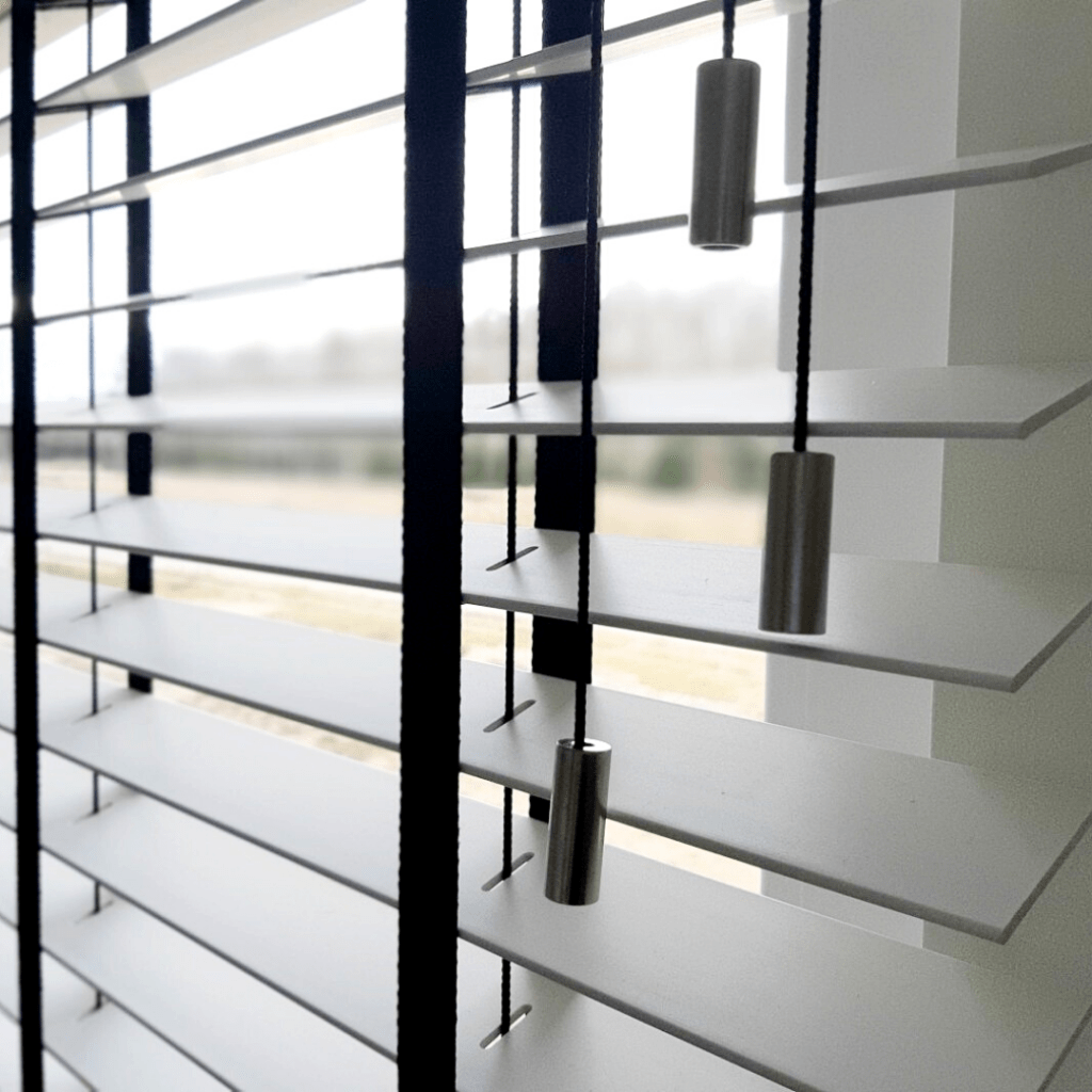 Białe żaluzje drewniane z czarną taśmą