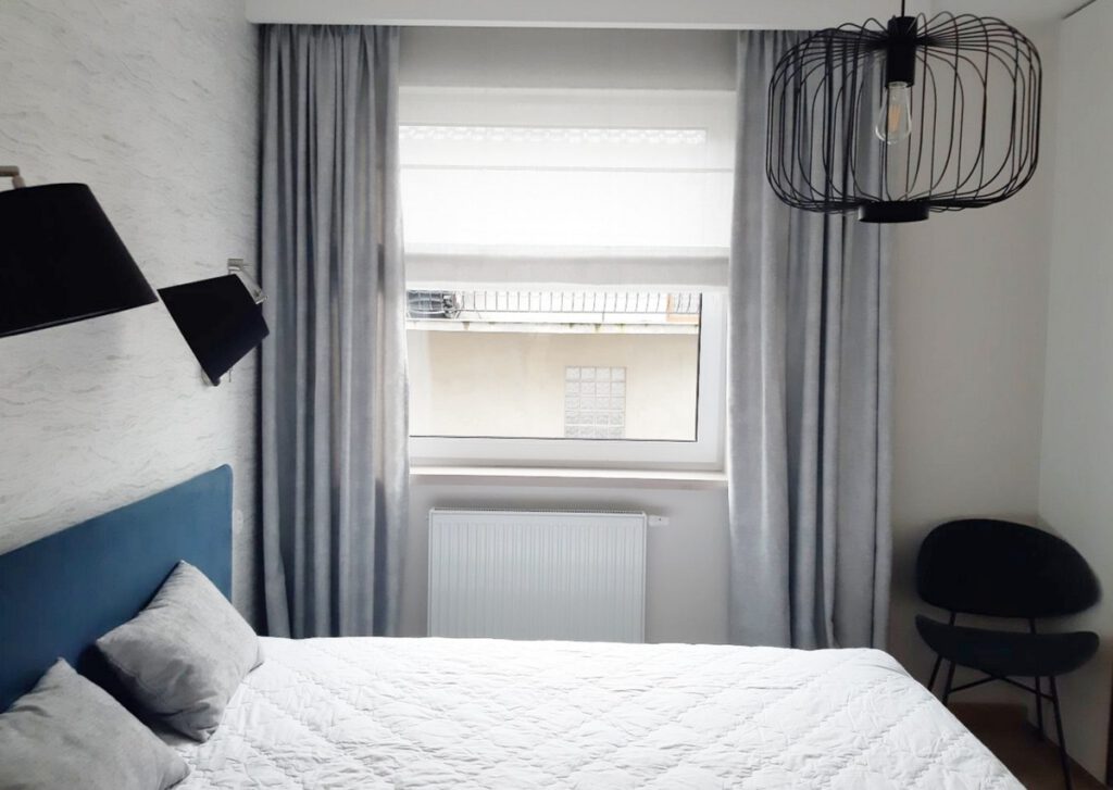 Szare zasłony i roleta rzymska w sypialni